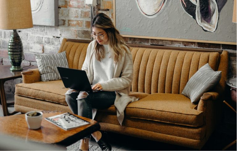 Woman sitting on a sofa, using a laptop